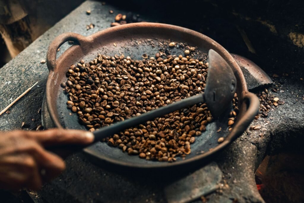Traditional coffee bean roasting in a clay pan over an open fire on a Costa Rica coffee farm tour, with a hand stirring the beans with a wooden paddle