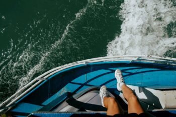 Passenger's feet dangling over the bow of the blue Puntarenas to Paquera ferry as it crosses the Gulf of Nicoya in Costa Rica with white water churning below