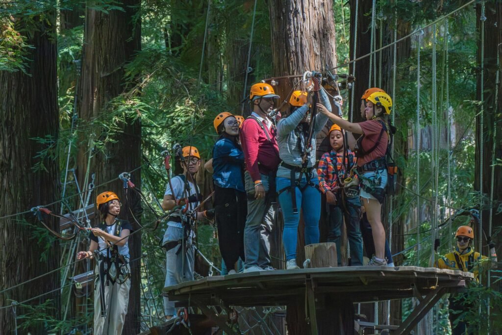 Group of visitors in orange helmets and harnesses preparing for a zipline canopy tour on a treetop platform in the cloud forest at Selvatura Park, Monteverde