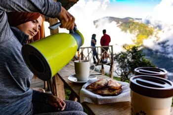 Pouring fresh coffee at a mountainside breakfast overlooking the clouds, similar to a morning in the Orosi Valley