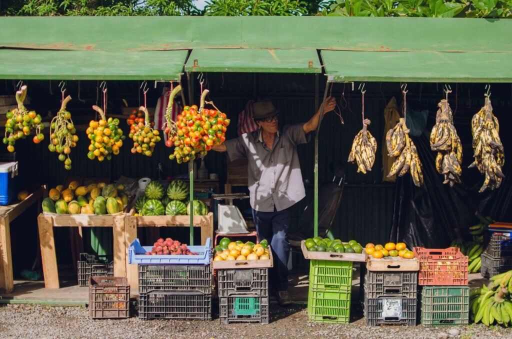 A vendor at a colorful roadside fruit stand in rural Costa Rica, similar to stops along the Orosi Valley drive