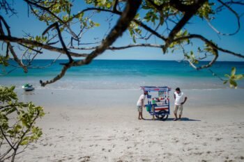 Costa Rican beach vendor cart on white sand with a jet ski on the turquoise water beyond