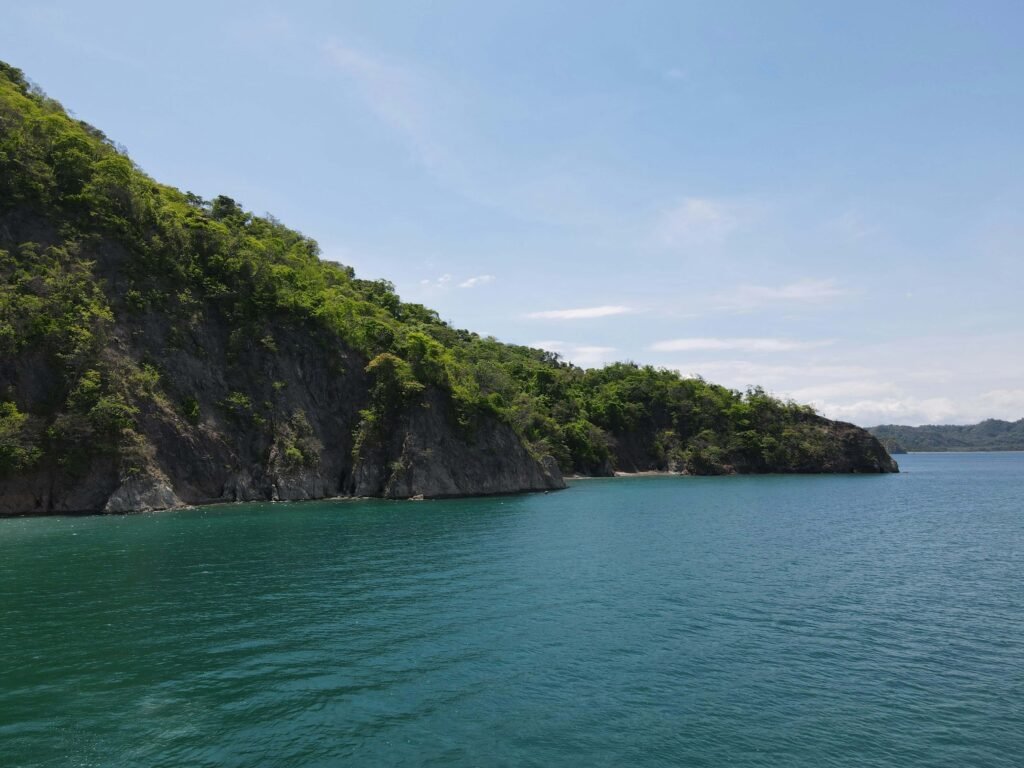 Forested rocky headland and turquoise water seen from a boat in the Gulf of Nicoya