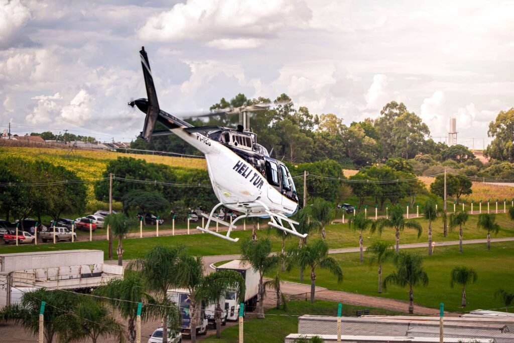 White tour helicopter lifting off above green fields and palm trees, similar to a scenic helicopter flight in Costa Rica