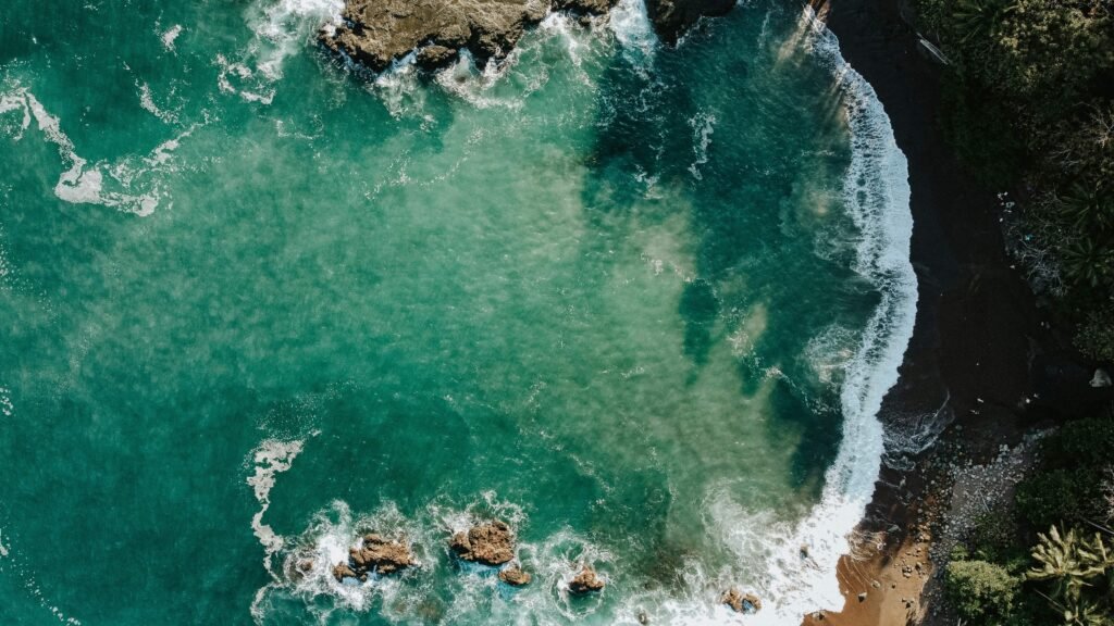 Aerial view of a secluded cove with rocky outcrops and turquoise water, similar to the coast near Playa Cocolito, Costa Rica